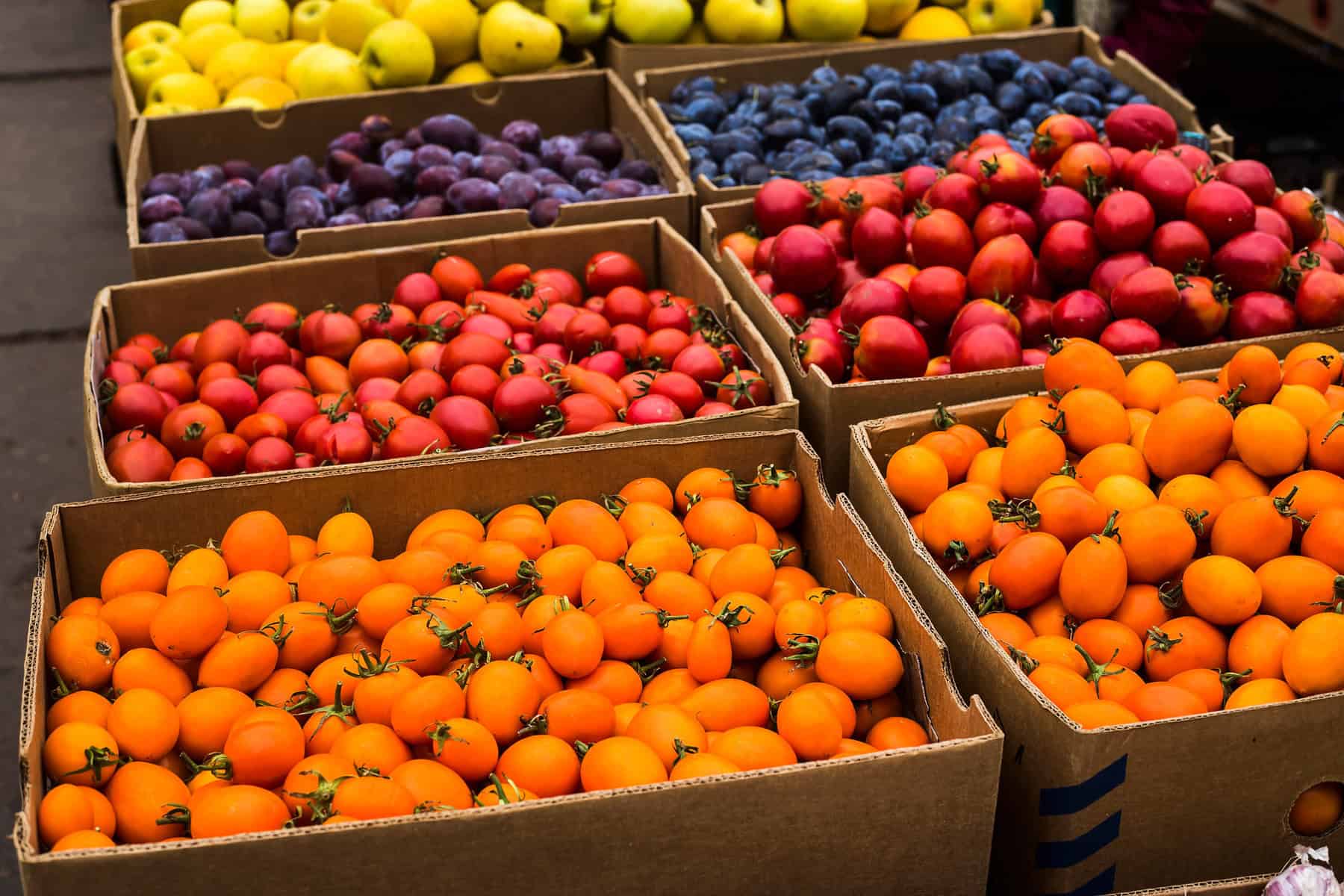 Small organic yellow and red tomatoes on the market in large boxes. Autumn Harvest Concept